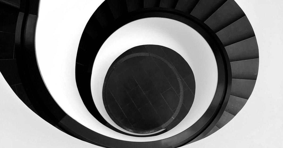 Black spiral staircase winding down a white stairwell